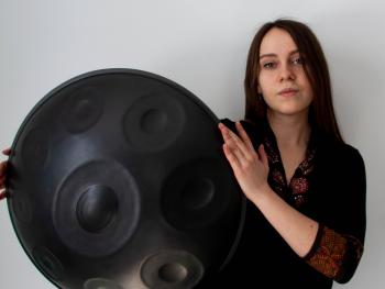 młoda kobieta w czarnej bluzce z trzymająca instrument handpan