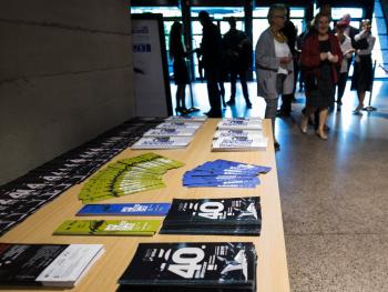 foyer sali koncertowej, pierwszy plan - stół na ktorym eksponowane są meteriały promocyyjne Dni Moniuszkowski, drugi plan - wejście główne do budynku CKK Jordanki, poprzez które  tłumnie kroczą melomani