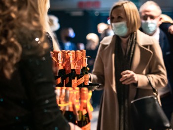 Kobieta odbierająca butelkę szampana po koncercie, tuż przy wyjściu z budynku