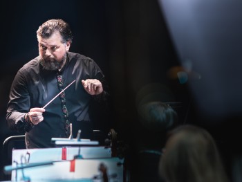 portret mężczyzny trzymającego w jednej ręce batutę